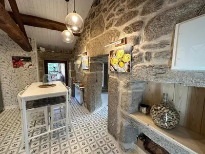 a kitchen with a stone wall with a table and a fireplace at Casa Camu in Covelo