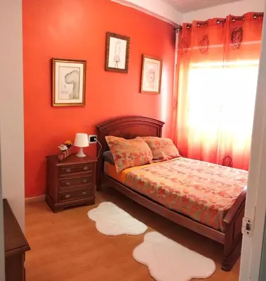 a bedroom with orange walls and a bed and a window at Piso Bonhome in Ourense