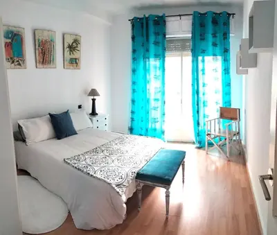 a bedroom with a large bed with blue curtains at Piso Bonhome in Ourense