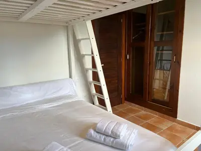 a bed in a room with a ladder next to it at O canto do grilo in Valeije