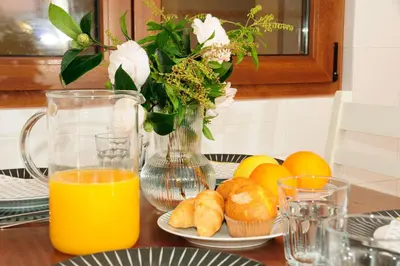 a table with oranges and a vase of flowers and orange juice at Silleda Via da Plata in Silleda