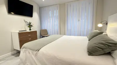 a bedroom with a bed and a dresser with a television at Apartamento Ourense Vello - en el centro del casco histórico in Ourense
