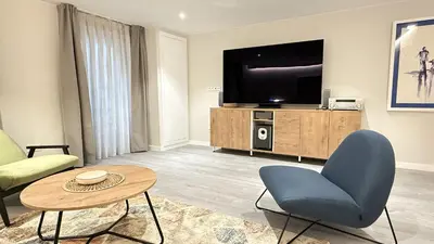 a living room with a tv and a blue chair at Apartamento Ourense Vello - en el centro del casco histórico in Ourense