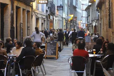 a group of people sitting at tables in a street at Motel Cancun Barbadas-Ourense in Os Fornos
