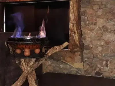 a stone fireplace with a pot with fire in it at Motel Cancun Barbadas-Ourense in Os Fornos