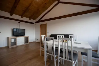 a dining room with a table and chairs and a tv at Refuxio de Lamas in Becerreá