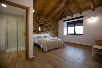 a bedroom with a bed and a glass shower at Refuxio de Lamas in Becerreá