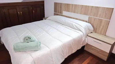 a bedroom with a white bed with a green bag on it at Vacansis Santiago Garcia Prieto y Romero Donallo Habitaciones Privadas in Santiago de Compostela