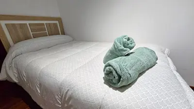 a green towel is laying on a bed at Vacansis Santiago Garcia Prieto y Romero Donallo Habitaciones Privadas in Santiago de Compostela