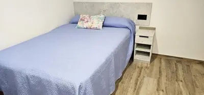 a bedroom with a bed with a pillow and a shelf at Vacansis Santiago Garcia Prieto y Romero Donallo Habitaciones Privadas in Santiago de Compostela