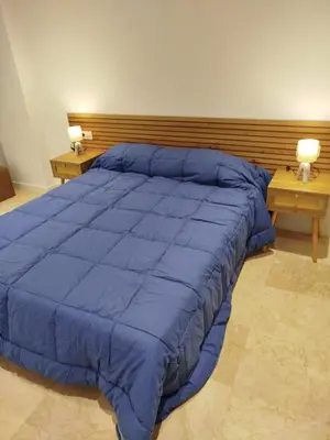 a bed with a blue comforter in a bedroom at XELIÑA d in A Estrada