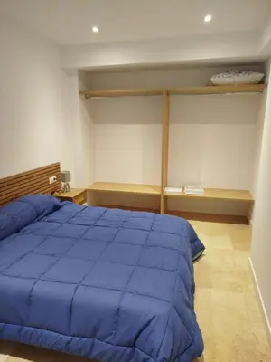 a bedroom with a large blue bed and shelves at XELIÑA d in A Estrada