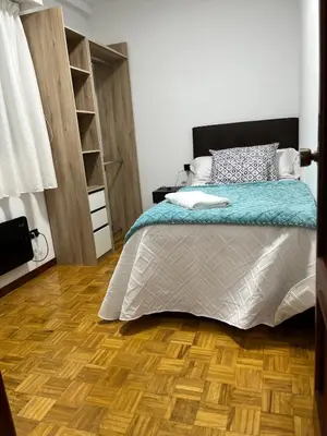 a bedroom with a bed and a wooden floor at Piso Artur III UNIVERSIDAD in Ourense