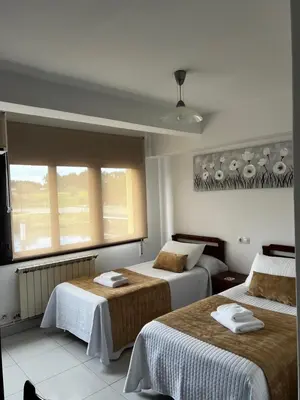 a hotel room with two beds and a window at Pensión Bodega de Ana in San Ciprián