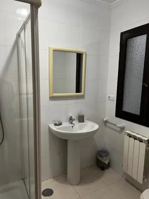 a white bathroom with a sink and a mirror at Pensión Bodega de Ana in San Ciprián