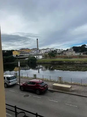 a red car parked in a parking lot next to a river at Pensión Bodega de Ana in San Ciprián