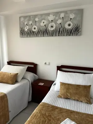 a bedroom with two beds and a painting of white flowers at Pensión Bodega de Ana in San Ciprián