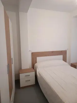 a small bedroom with a bed and a night stand at Piso en Pontedeume enfrente hotel Eumesa in Puentedeume