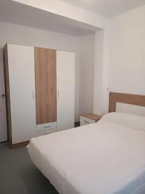 a bedroom with a white bed and a cabinet at Piso en Pontedeume enfrente hotel Eumesa in Puentedeume