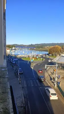 a street with cars parked next to a harbor at Piso en Pontedeume enfrente hotel Eumesa in Puentedeume