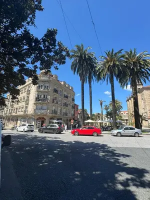 a red car parked in front of a building with palm trees at Caldas no Camiño in Caldas de Reis