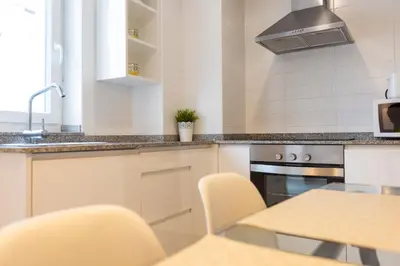 a kitchen with white cabinets and a table with chairs at Casiña da Ribeira in Foz