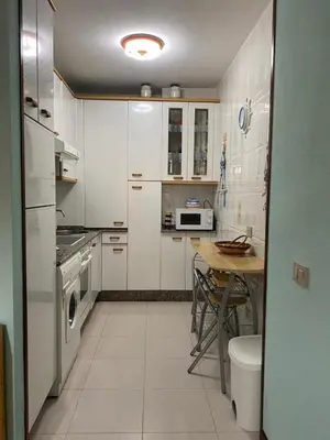 a kitchen with white cabinets and a table in it at Playa a Rapadoira - Foz in Foz