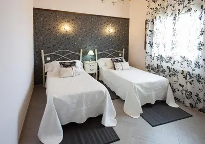 a room with two beds with white sheets and a window at El Capricho de Gonzalo in Cartavio