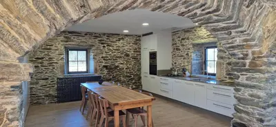 a kitchen with a table and a stone wall at Casa Escuela Sanguñedo in Magdalena