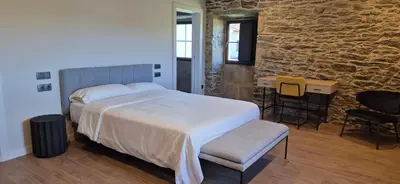 a bedroom with a large bed and a stone wall at Casa Escuela Sanguñedo in Magdalena