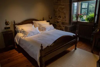 a bedroom with a bed with white sheets and pillows at Casal de Armán in Camporredondo