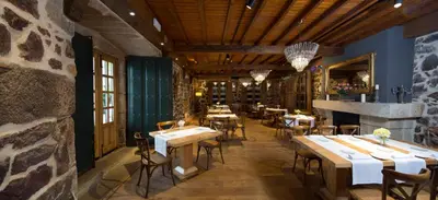 a restaurant with tables and chairs and a stone wall at Casal de Armán in Camporredondo