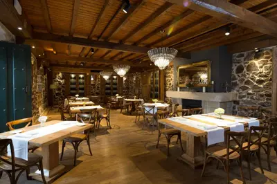 a restaurant with wooden tables and chairs and a stone wall at Casal de Armán in Camporredondo