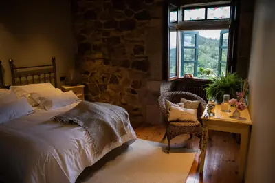 a bedroom with a bed and a desk and a window at Casal de Armán in Camporredondo