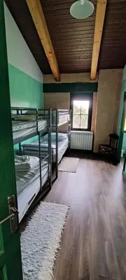 a room with three bunk beds and a ceiling at Alberguecasaflor in Murias de Rechivaldo