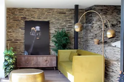 a yellow couch in a room with a brick wall at Hotel Apartamentos Casas da Fortaleza in Lugo