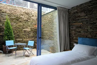 a bedroom with a bed and a table and chairs at Hotel Apartamentos Casas da Fortaleza in Lugo