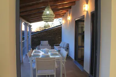 a table and chairs on a patio with a chandelier at Hotel Apartamentos Casas da Fortaleza in Lugo
