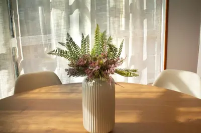 a white vase with flowers sitting on a table at A Paradiña de Sarria in Sarria