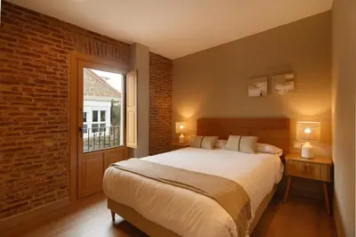 a bedroom with a large bed and a brick wall at Casa San Blas in Verín