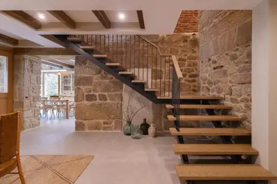 a wooden staircase in a room with a stone wall at Casa San Blas in Verín