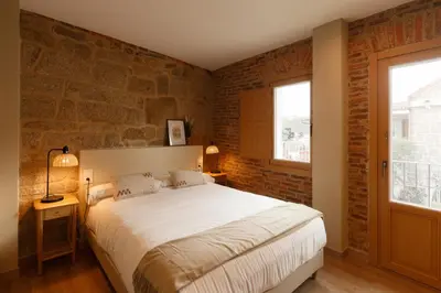 a bedroom with a large bed and a brick wall at Casa San Blas in Verín
