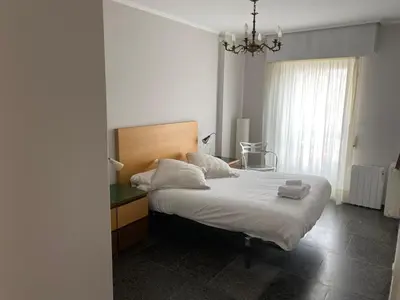 a bedroom with a bed with white sheets and a chandelier at Vistas do Eume in Puentedeume
