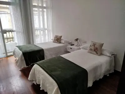 two beds sitting in a room with windows at Pensión 5 Caminos in Santiago de Compostela