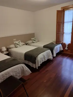 a bedroom with two beds and a wooden floor at Pensión 5 Caminos in Santiago de Compostela