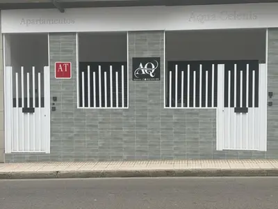 a brick building with four white doors on it at Aqua Celenis in Caldas de Reis