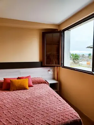 a bedroom with a bed and a large window at Hostal Restaurante LA SENDA in Camponaraya