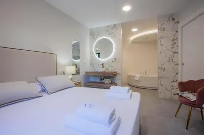 a white bedroom with a large bed and a bathroom at Apartamentos PUERTO DE VIAVELEZ in Viavélez