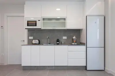 a kitchen with white cabinets and a refrigerator at Apartamentos PUERTO DE VIAVELEZ in Viavélez