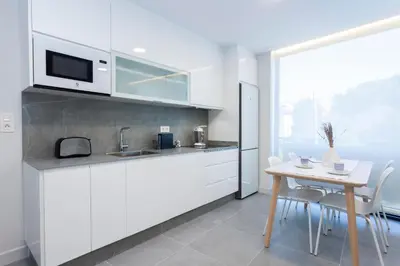 a kitchen with white cabinets and a table with chairs at Apartamentos PUERTO DE VIAVELEZ in Viavélez